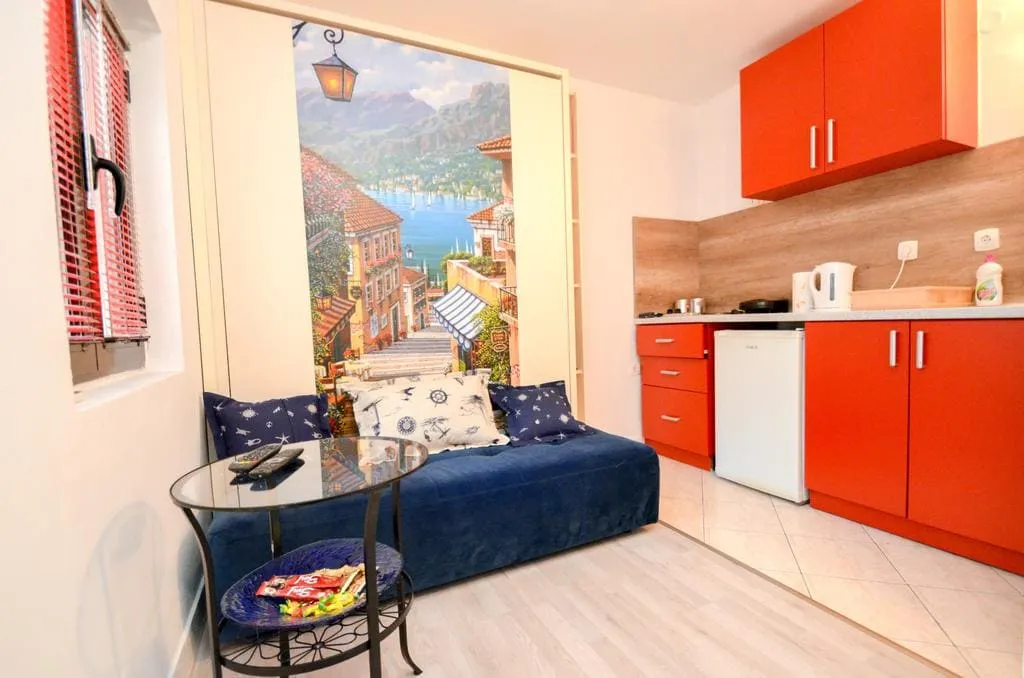 Living room with a bright kitchen and sofa in a house in Kotor, Montenegro: modern interior with photo wallpaper and a seating area.