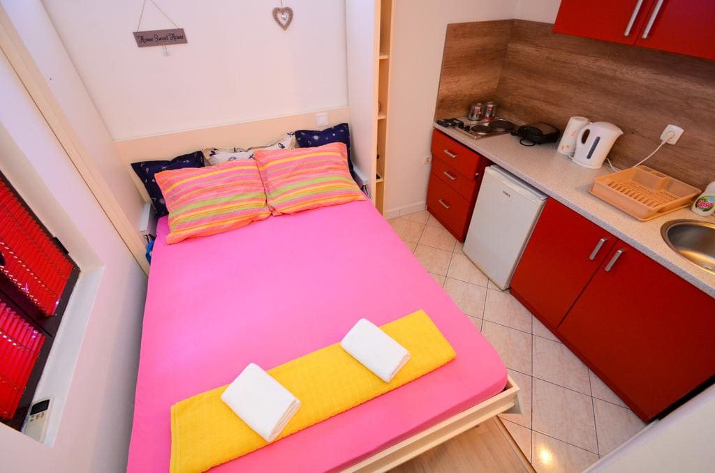 Kompaktes Schlafzimmer mit Doppelbett und Einbauküche in den Apartments, Stadt Kotor, Montenegro.