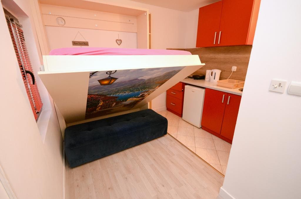 Kompaktes Schlafzimmer mit Klappbett und Küchenzeile in einem Haus in Kotor, Montenegro. Moderne Ausstattung und Möbel.
