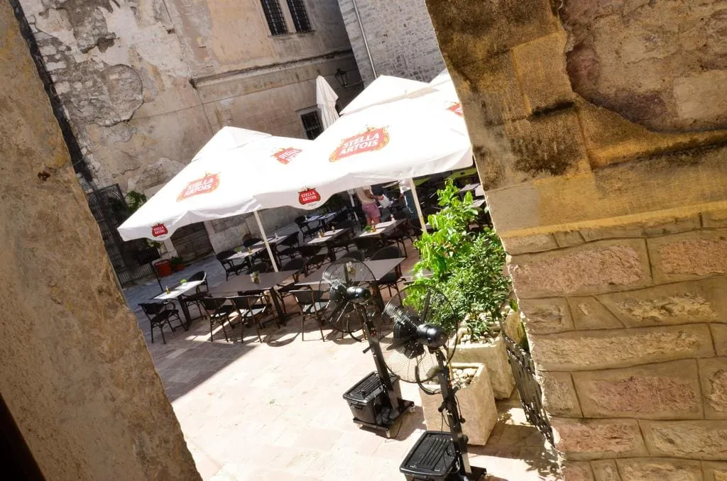 Cozy restaurant terrace in the old town of Kotor, Montenegro: tables under umbrellas and stone architecture of the buildings.