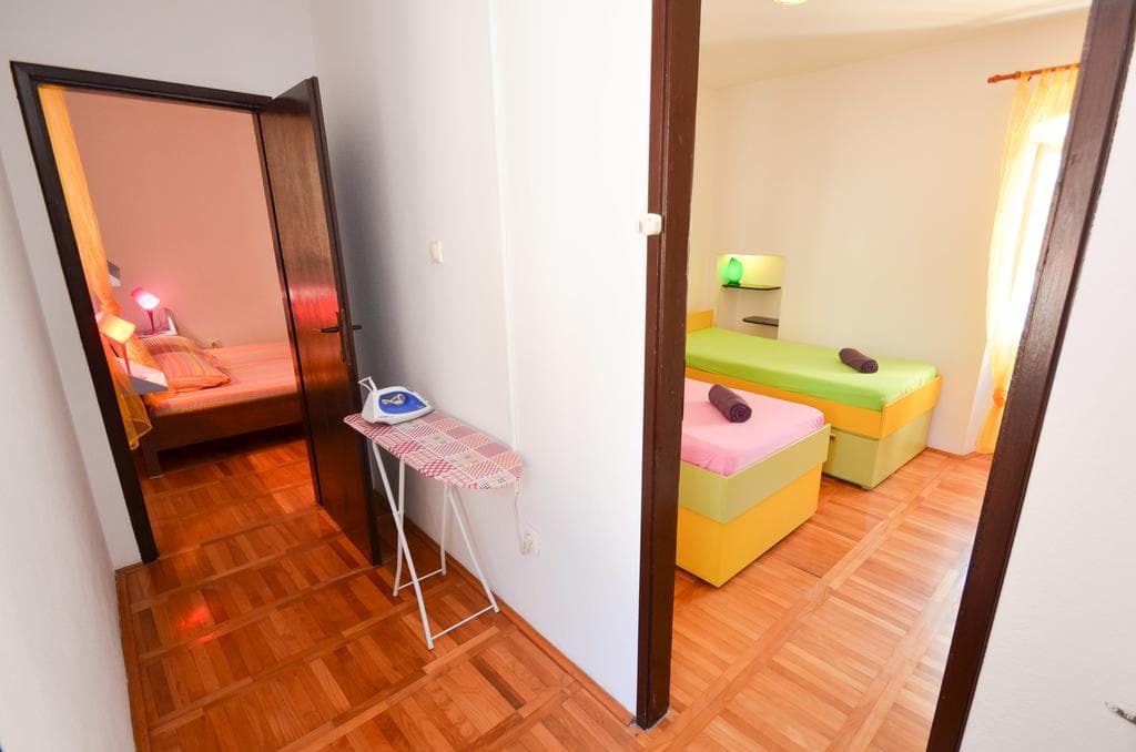 Zwei Schlafzimmer mit Einzelbetten und Parkett in einem Haus in Kotor, Montenegro. Gemütliches Interieur mit Bügelbrett.