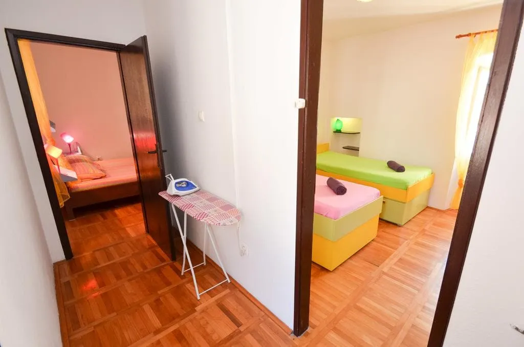 Two bedrooms with single beds and parquet flooring in a house in Kotor, Montenegro. Cozy interior with an ironing board.
