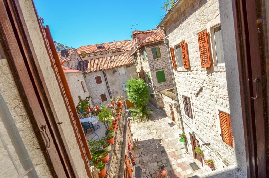 Blick aus dem Fenster auf einen gemütlichen steinernen Innenhof und alte Häuser mit Ziegeldächern in der Altstadt von Kotor, Montenegro.
