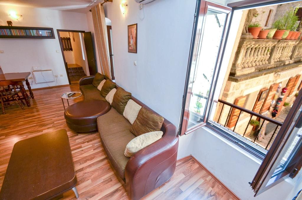 Wohnzimmer mit Ledersofa und Blick auf die Altstadt in einem Haus in Kotor, Montenegro: Innenraum mit Holzboden.