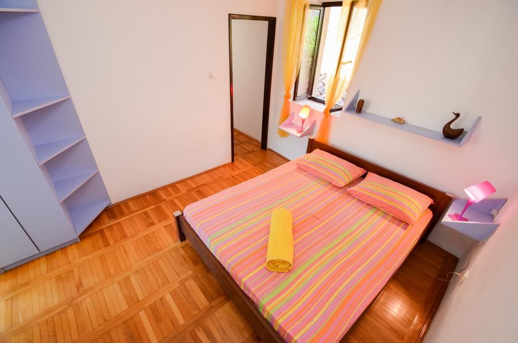 Schlafzimmer mit Doppelbett, Parkett und hellem Interieur in einem Haus zum Verkauf, Kotor, Montenegro.