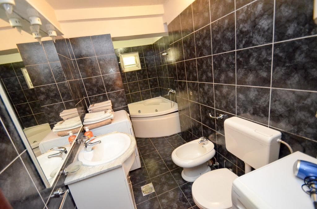 Badezimmer mit Eckbadewanne und dunklen Fliesen in einem Haus zum Verkauf in Kotor, Montenegro.