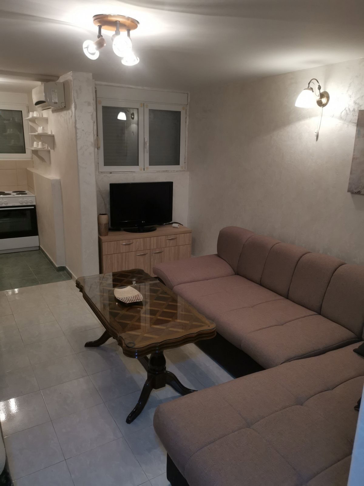 Wohnzimmer mit weichem Sofa und Couchtisch in einer Wohnung in Budva, Montenegro: helles Interieur und Küchenbereich.