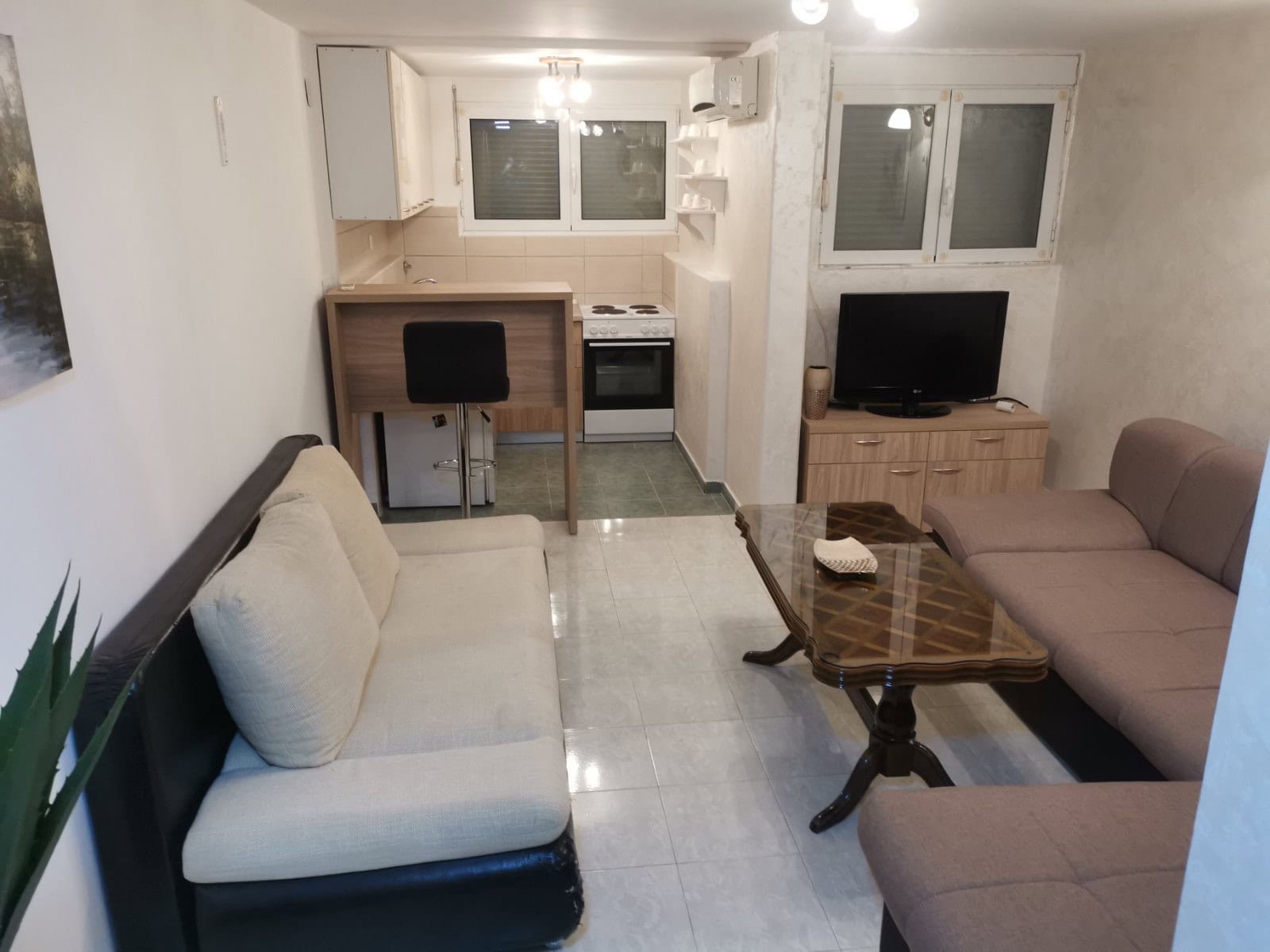 Wohnzimmer mit Küche in einer Wohnung in Budva, Montenegro: zwei Sofas, Couchtisch, Bartheke und Küchenbereich.