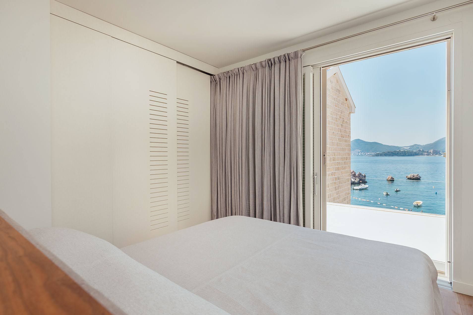 Bedroom in a villa in Pržno, Montenegro: bright interior, built-in wardrobe, and panoramic sea and mountain views from the window.