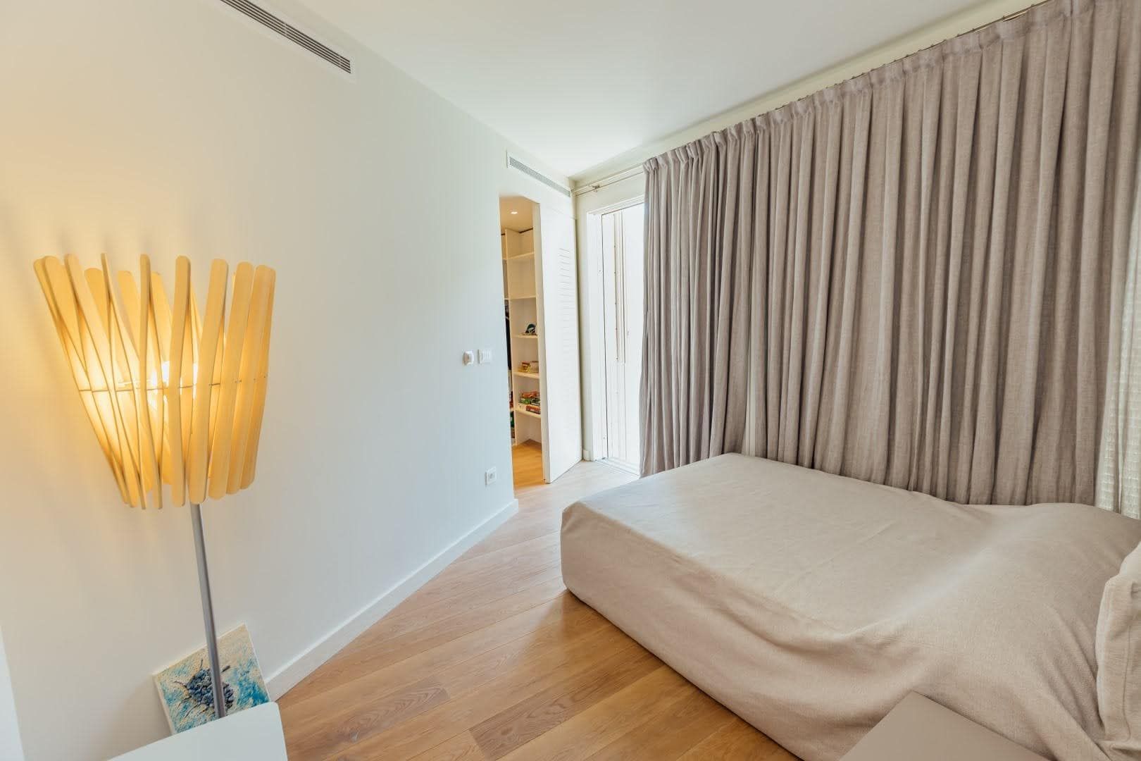 Modern bedroom with a double bed and walk-in closet in a villa in Pržno, Montenegro. Bright interior with a floor lamp.