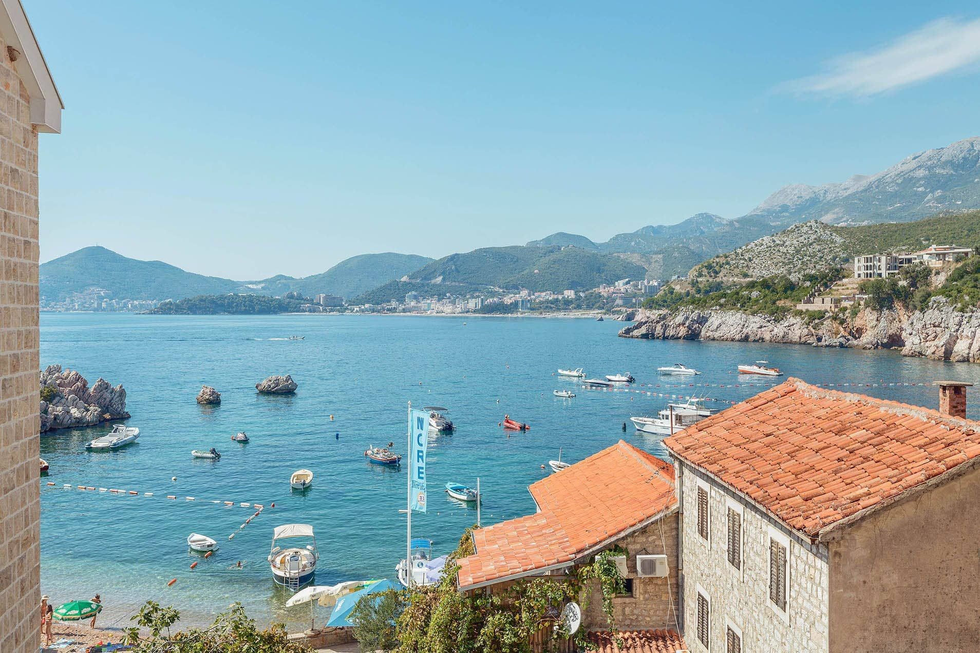 Panoramic view of the sea and Pržno Bay, Montenegro, from the villa terrace, stone houses with tiled roofs and boats.