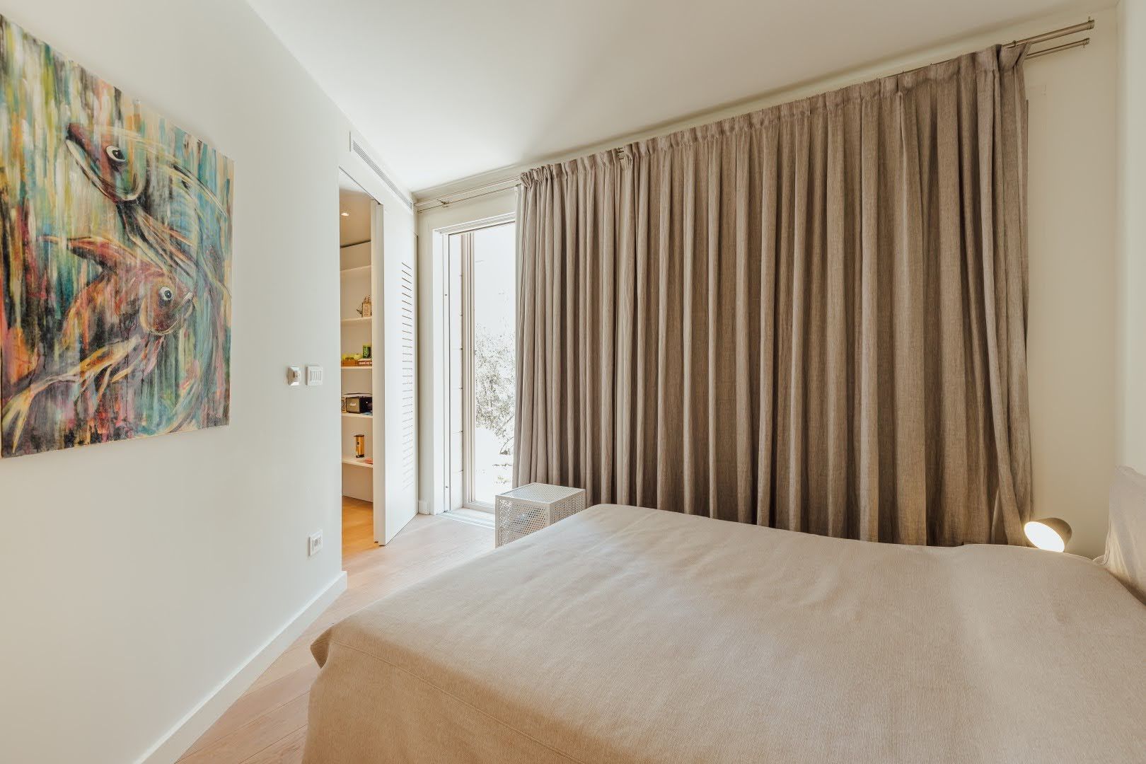 Bright bedroom in a villa in Pržno, Montenegro: double bed, fish painting, and access to the terrace.