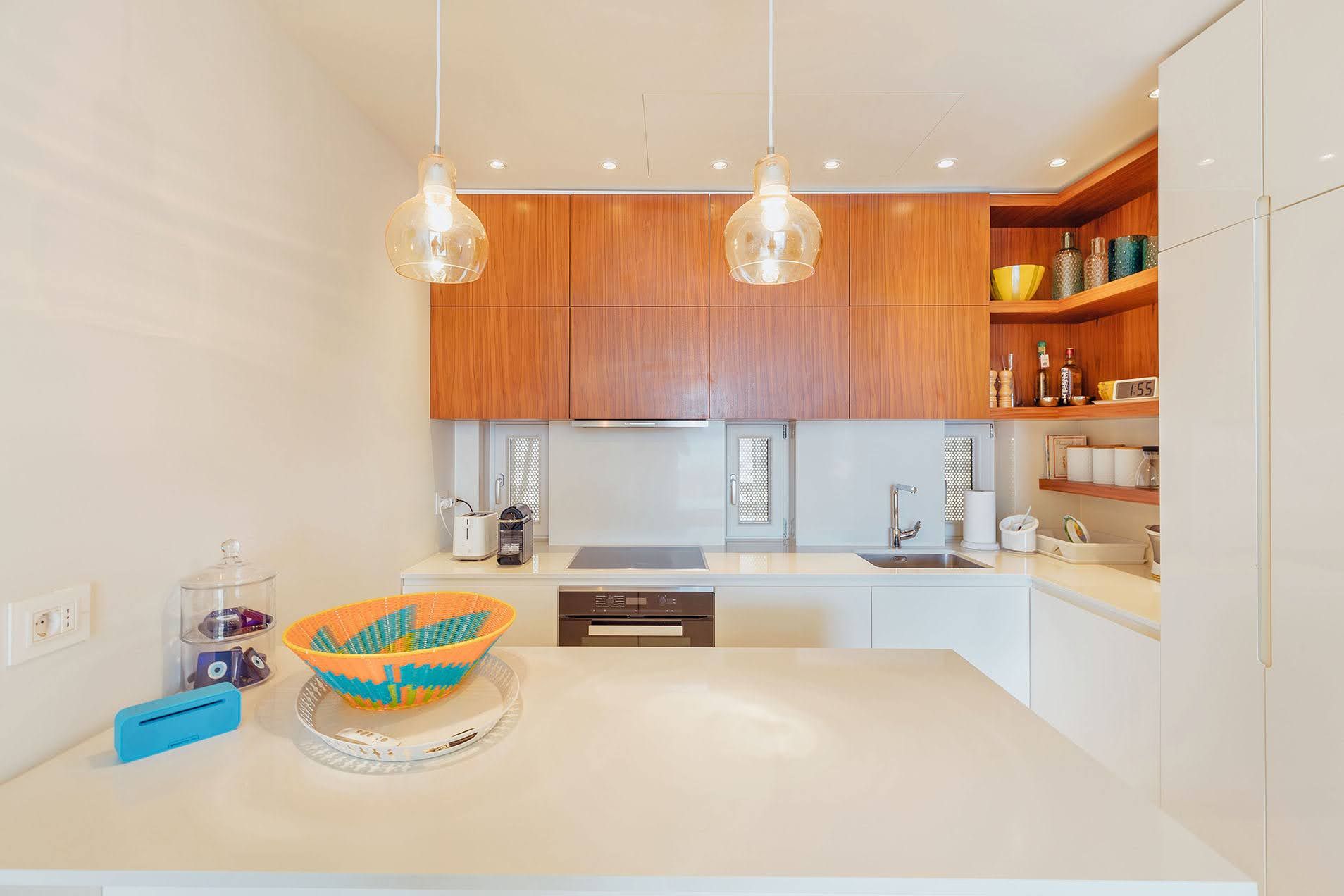 Modern kitchen with wooden fronts and a white countertop in a villa in Pržno, Montenegro.