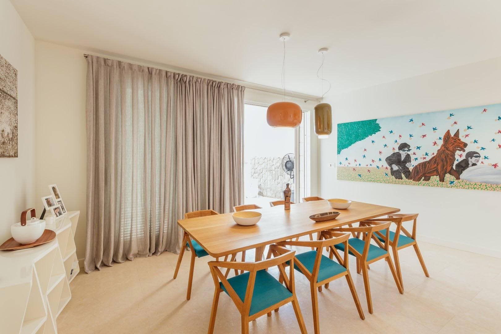 Modern dining area with a wooden table in a villa in Pržno, Montenegro: stylish interior and a bright painting.