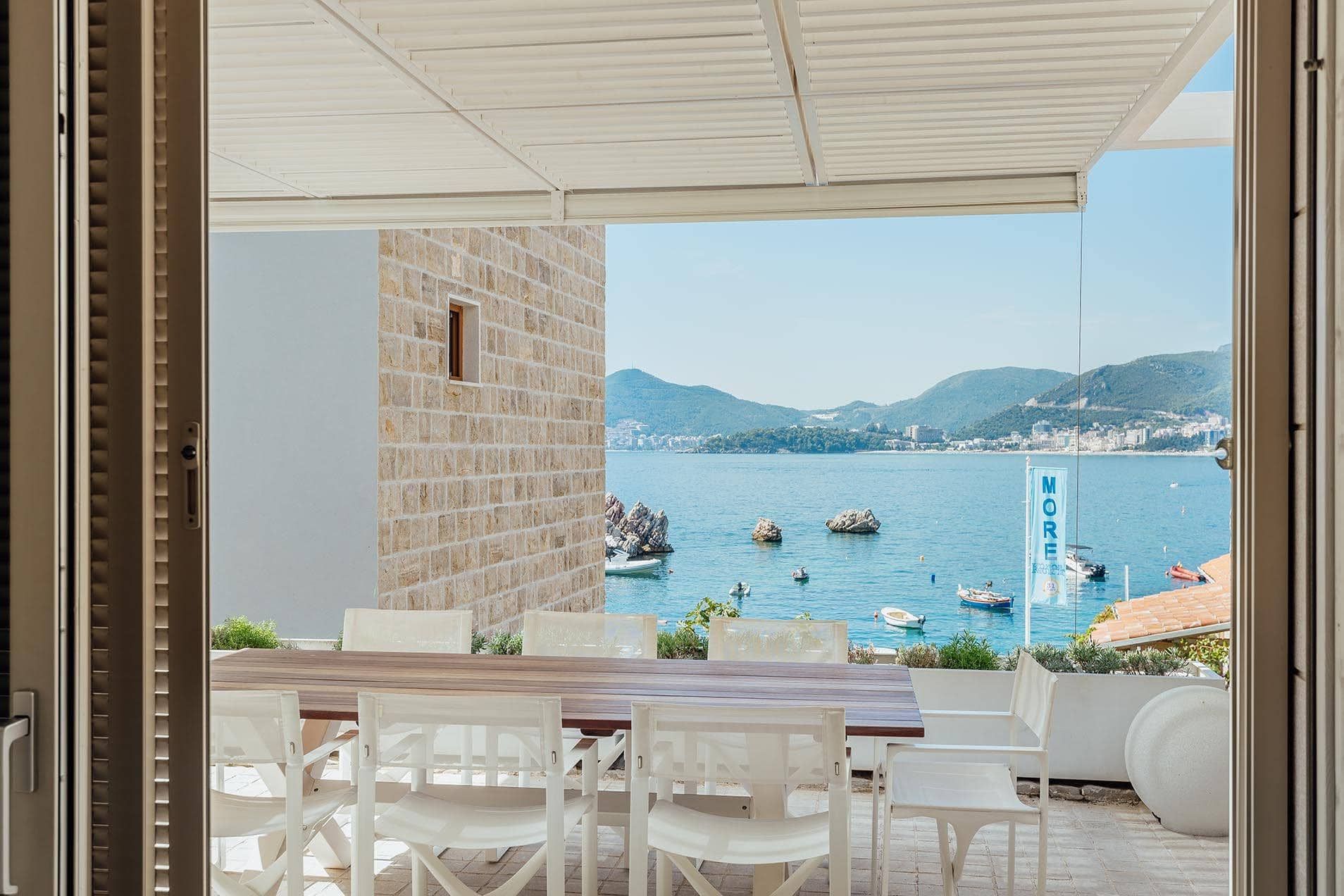 Villa terrace in Pržno, Montenegro: dining table, sea and mountain views, stone wall finish, sunshade.