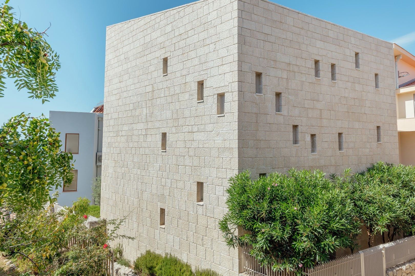 Modern villa with a natural stone facade in Pržno, Montenegro: exterior view of the building with narrow windows.