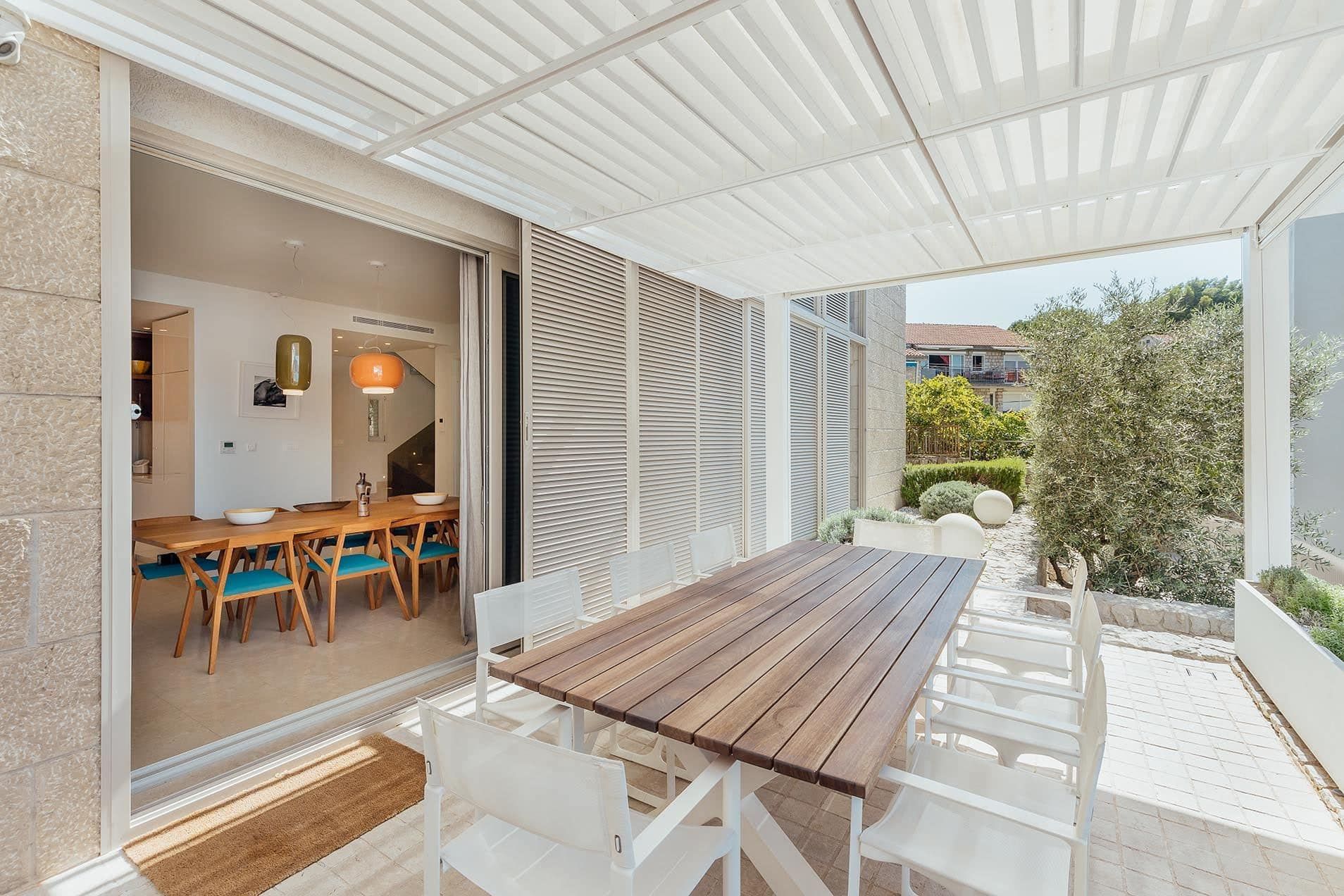 Villa terrace in Pržno, Montenegro: outdoor dining area, wooden table, modern design, and garden view.