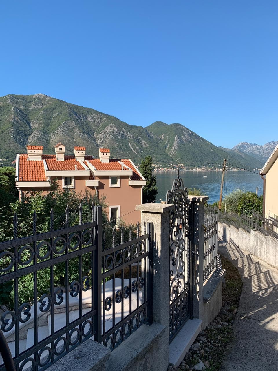 Pogled na vilu sa kovanom ogradom i panoramskim pogledom na Bokokotorski zaliv i planine, Dobrota, Crna Gora.