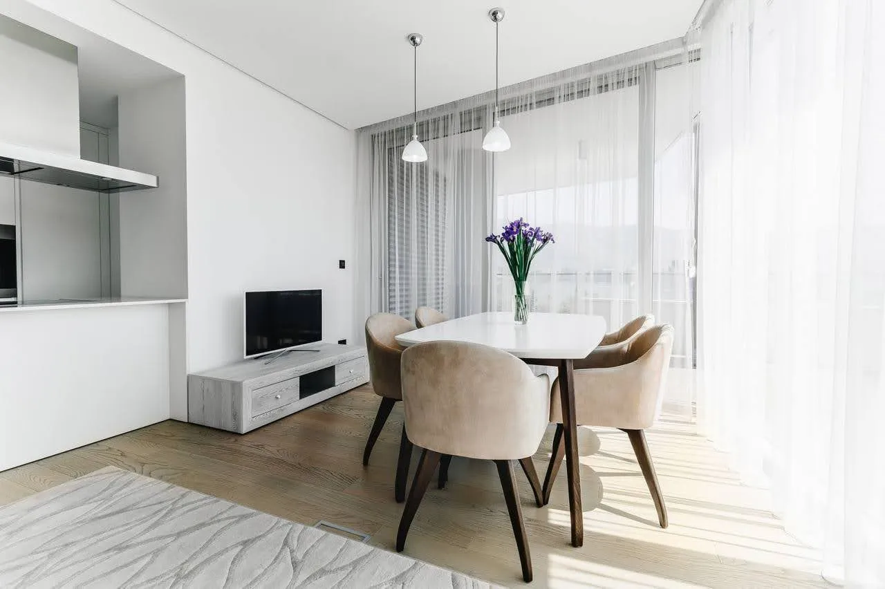Modernes Wohnzimmer mit Essbereich in einer Wohnung in Budva, Montenegro: helles Interieur, Panoramafenster und Möbel.