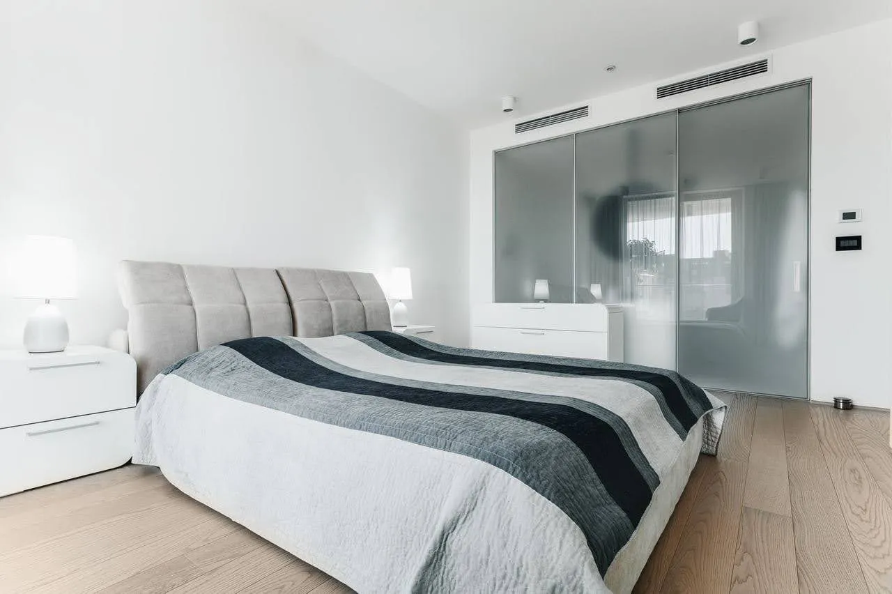 Modernes Schlafzimmer in einer Wohnung in Budva, Montenegro: Doppelbett, helles Interieur und ein Glas-Schiebetürenschrank.