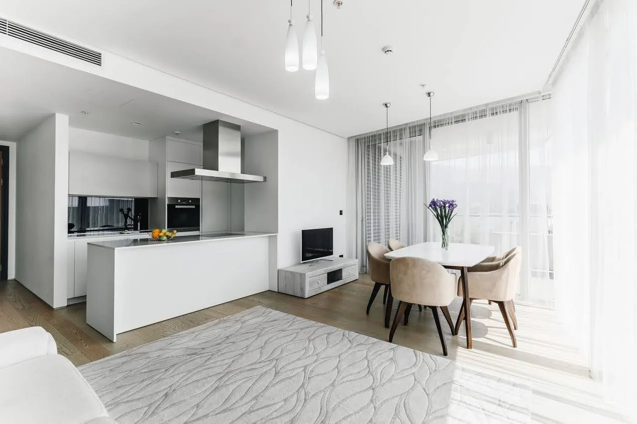 Modernes Wohnzimmer mit Küche in einer Wohnung in Budva, Montenegro: helles Interieur, Essbereich und Panoramafenster.