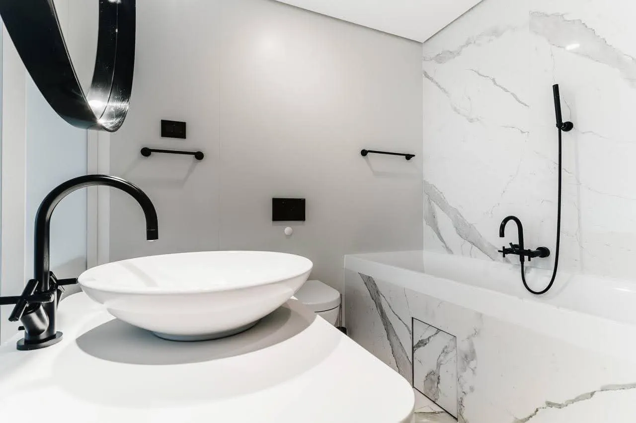Modernes Badezimmer in einer Wohnung in Budva, Montenegro: Marmoroptik, schwarze Armaturen und Aufsatzwaschbecken.