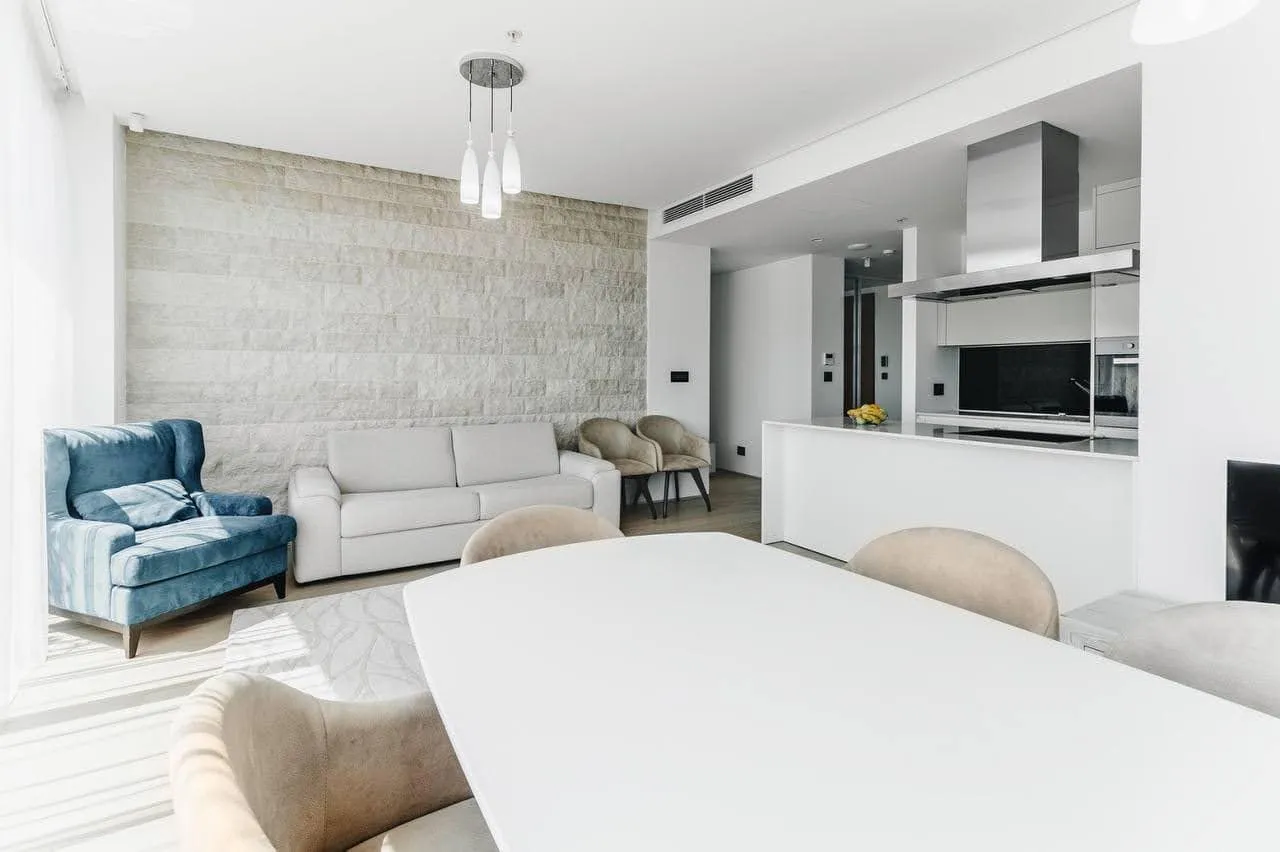 Modernes Wohnzimmer mit Steinwand und Küche in einer Wohnung in Budva, Montenegro: stilvolle Möbel und helles Interieur.