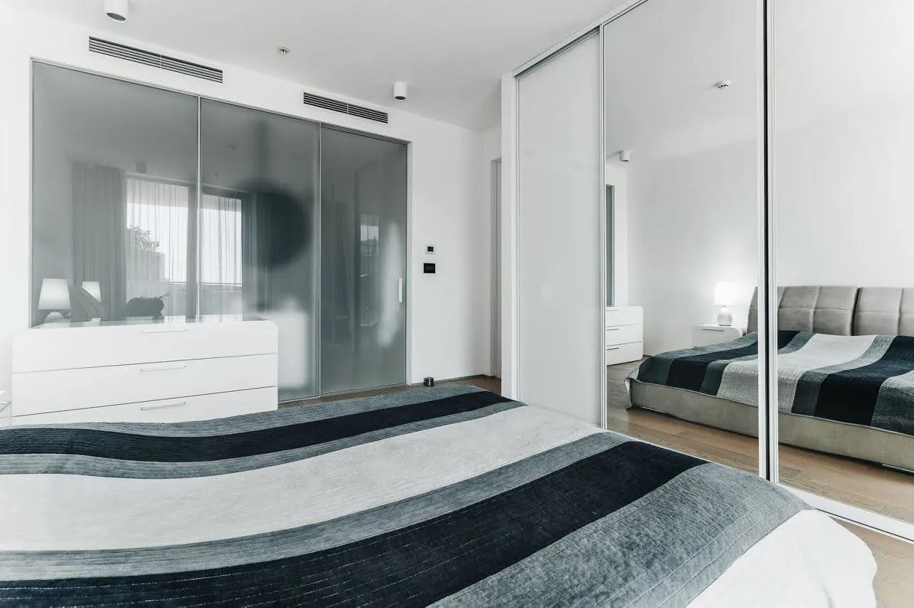 Modernes Schlafzimmer in einer Wohnung in Budva, Montenegro: Doppelbett, Kleiderschrank mit Spiegeltüren und helles Interieur.