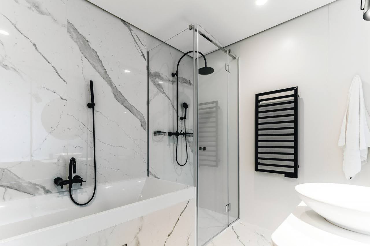 Budva, Karadağ’daki dairede duş kabinli ve mermer kaplamalı modern banyo.