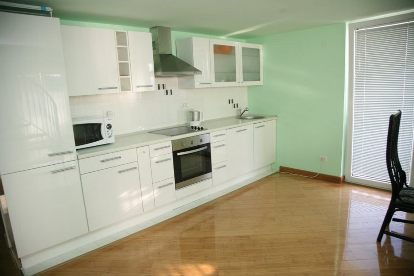 Moderne weiße Küche mit Geräten in einer Villa in Tivat, Montenegro: glänzende Fronten, helle Wände und Parkettboden.