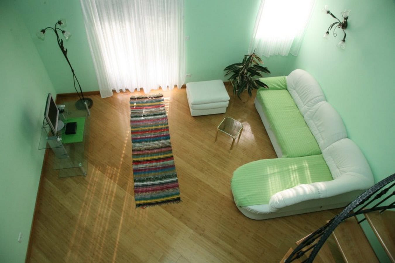Helles Wohnzimmer mit grünen Wänden, weißem Sofa und Holzboden in einer Villa in Tivat, Montenegro.