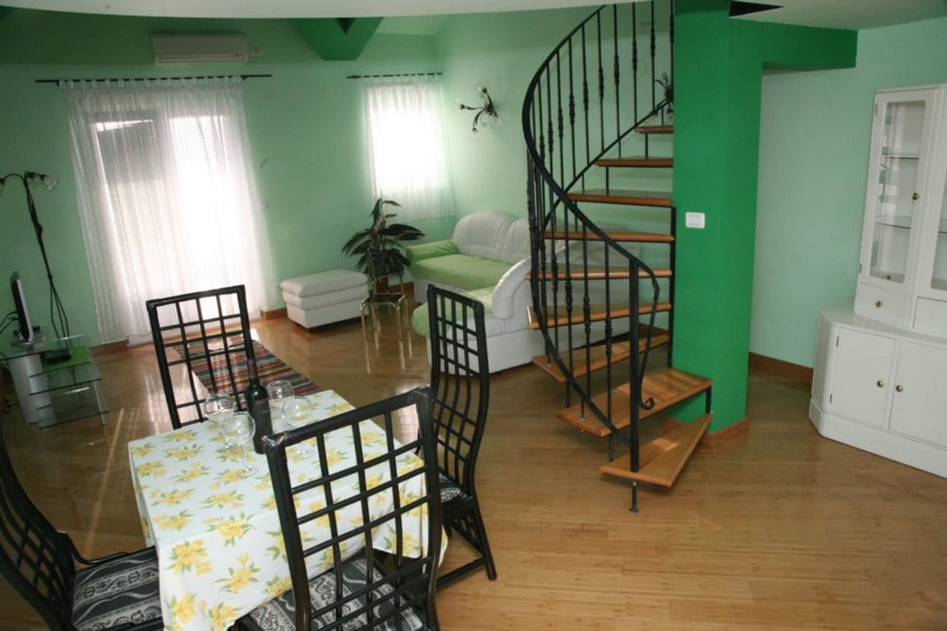 Wohnzimmer mit Wendeltreppe und Essbereich in einer Villa in Tivat, Montenegro: helles Interieur, Holzboden.