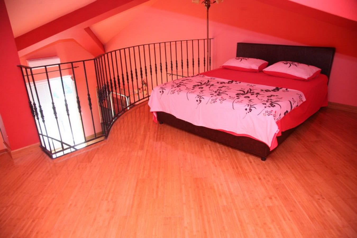 Schlafzimmer im Dachgeschoss einer Villa in Tivat, Montenegro: Doppelbett, Holzboden und schmiedeeisernes Geländer.