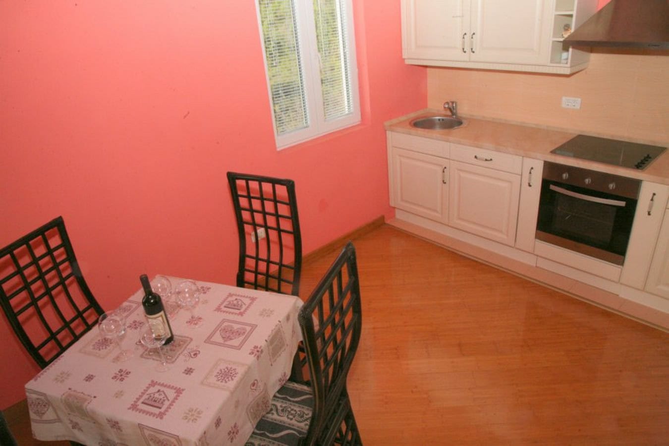 Küche mit weißer Einbauküche und Essbereich in einer Villa in Tivat, Montenegro: helle Möbel, integrierte Geräte.