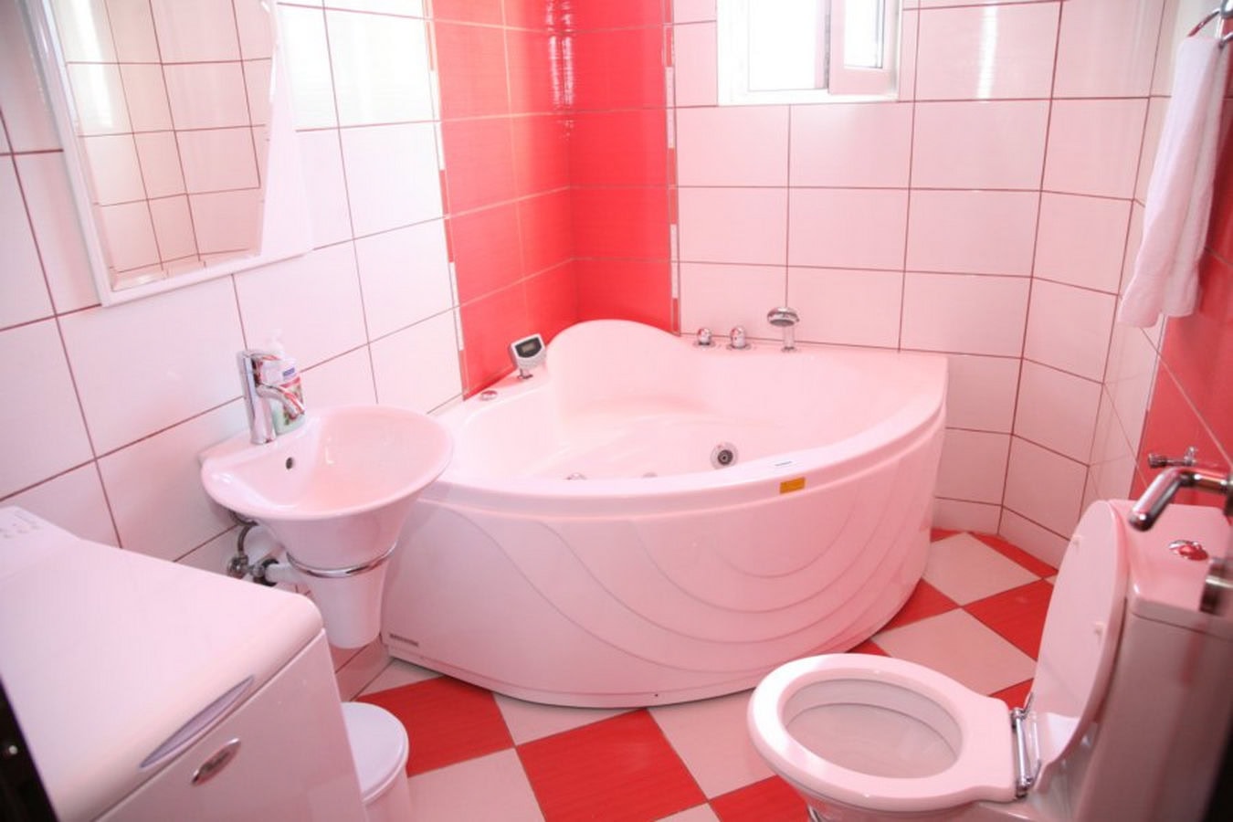 Badezimmer mit Eckbadewanne und rot-weißen Fliesen in einer Villa in Tivat, Montenegro.