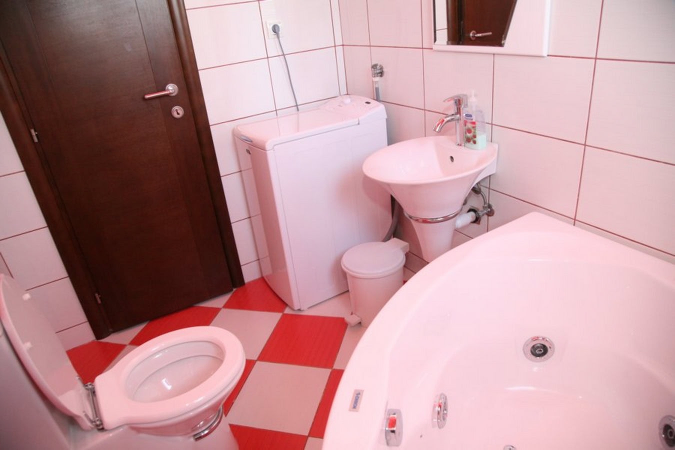 Badezimmer mit Whirlpool und Waschmaschine in einer Villa in Tivat, Montenegro: helle Fliesen und Sanitäranlagen.