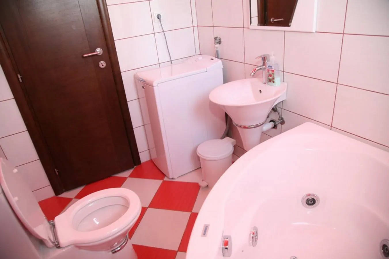 Łazienka z jacuzzi i pralką w willi w Tivacie, Czarnogóra: jasne płytki i armatura.