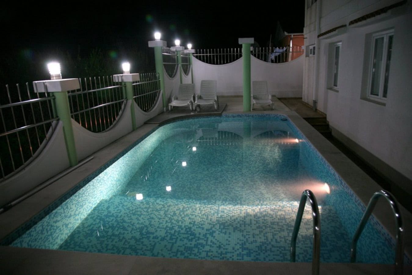 Privater Pool mit Beleuchtung und Liegestühlen auf der Terrasse der Villa in Tivat, Montenegro, am Abend.