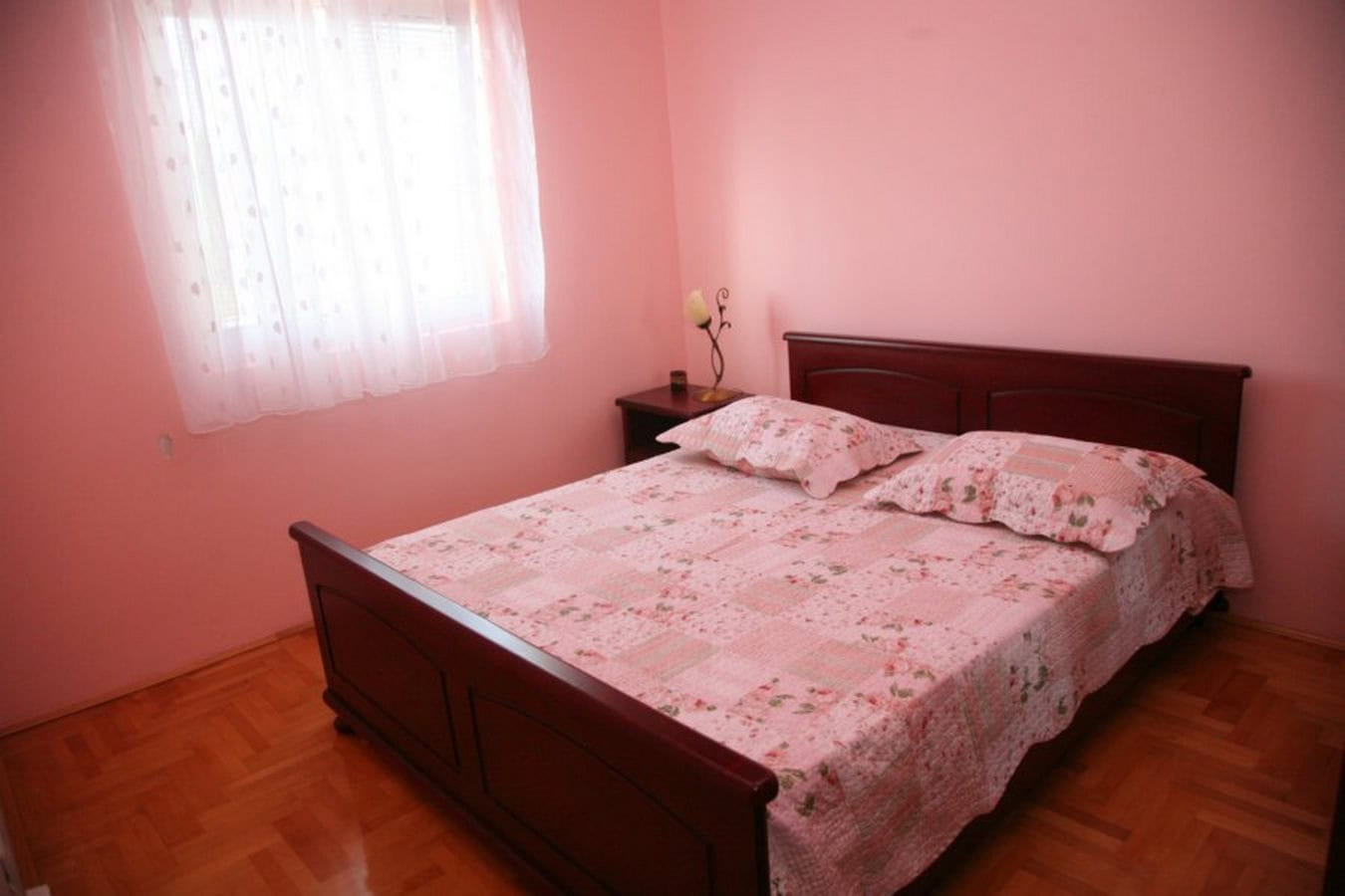 Schlafzimmer mit Doppelbett und Parkett in einer Villa in Tivat, Montenegro. Gemütliches Interieur in Rosatönen.