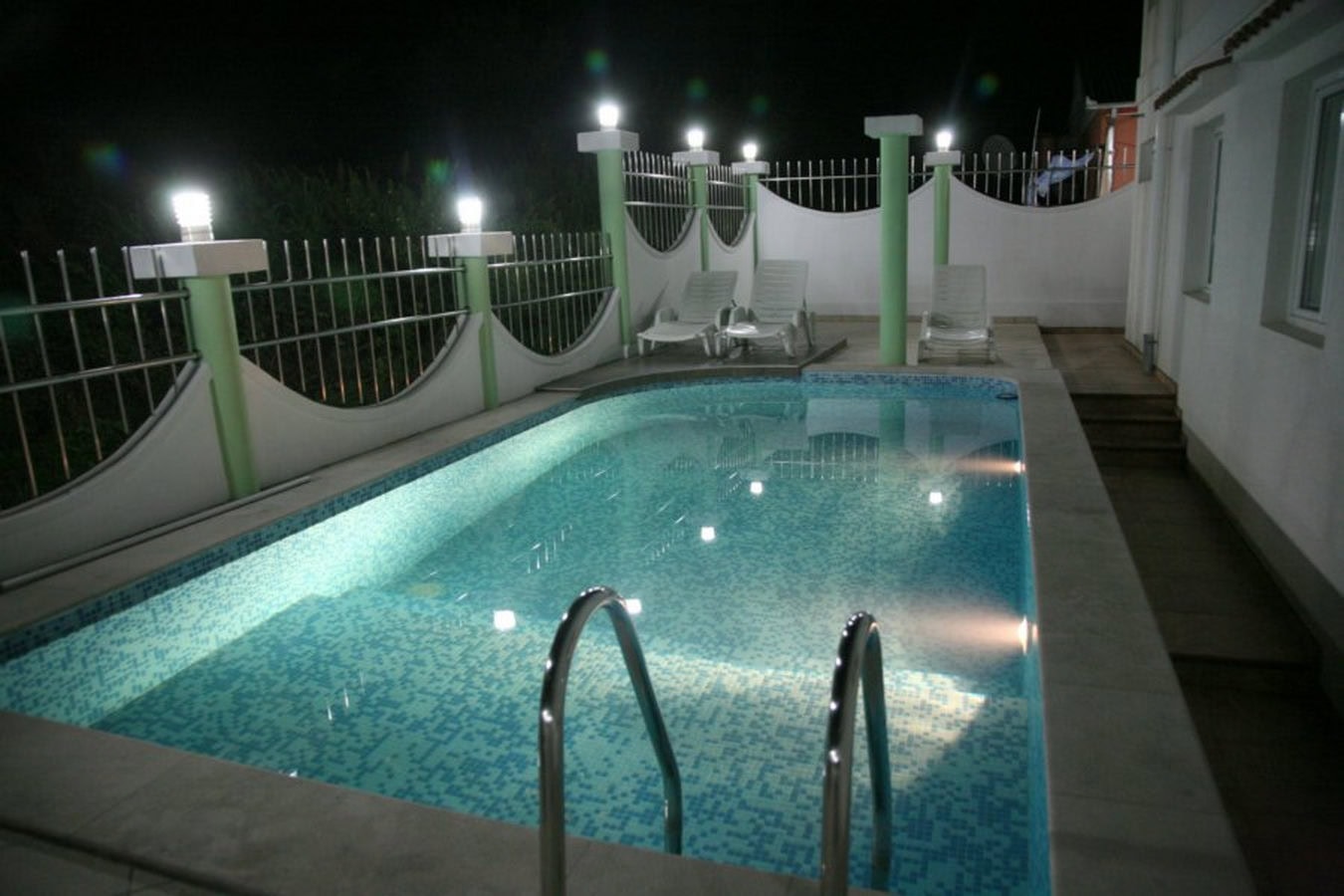 Privater Pool mit Beleuchtung und Sonnenliegen in einer Villa in Tivat, Montenegro, Blick auf die Terrasse bei Nacht.