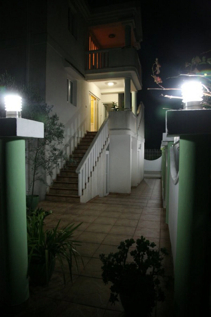 Nachtbeleuchtung der Fassade einer Villa in Tivat, Montenegro: Steintreppe, Terrasse und gepflegter Innenhof mit Pflanzen.