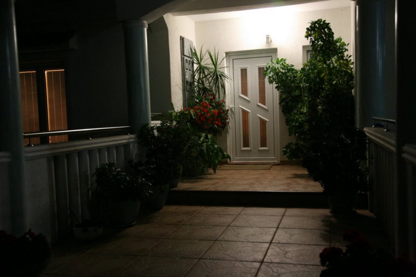 Abendterrasse der Villa in Tivat, Montenegro: Eingangstür, Fliesenboden und dekorative Topfpflanzen.