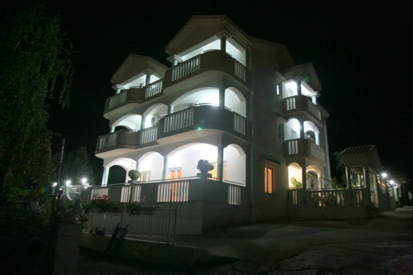 Dreistöckige Villa in Tivat, Montenegro, mit beleuchteten Terrassen und Balkonen bei Nacht.