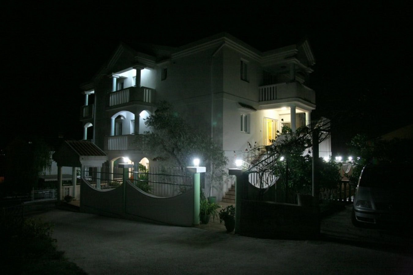 Dreistöckige Villa in Tivat, Montenegro, mit Nachtbeleuchtung, Terrassen und eingezäuntem Grundstück.