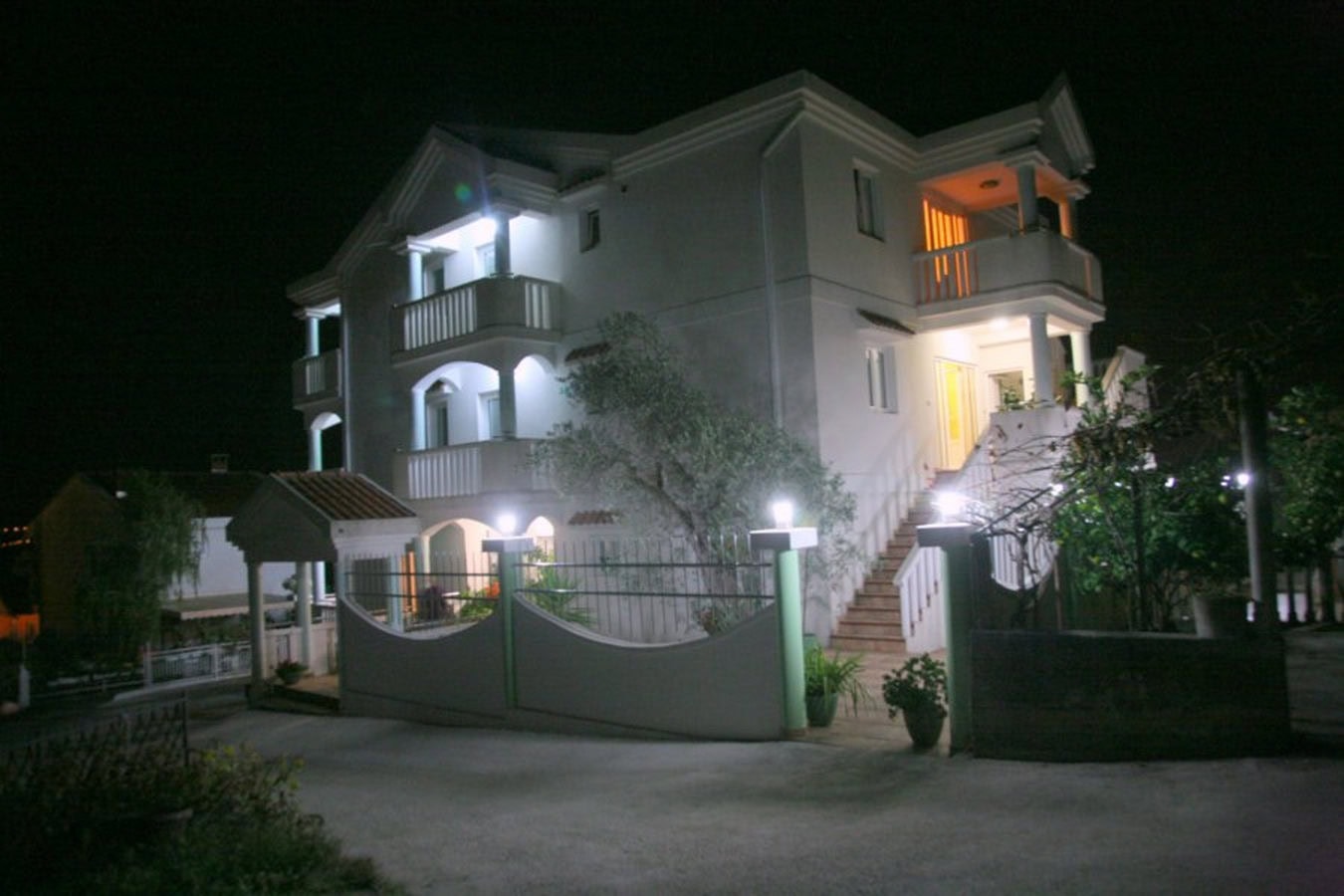 Dreistöckige Villa in Tivat, Montenegro: Fassade mit Beleuchtung, Balkonen und Treppe bei Nacht.