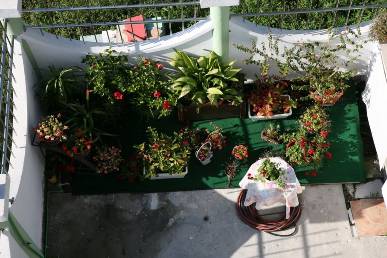 Gemütlicher Balkon mit Blumen und grünem Belag auf einer Villa in Tivat, Montenegro: Draufsicht auf die Terrasse mit Pflanzen.