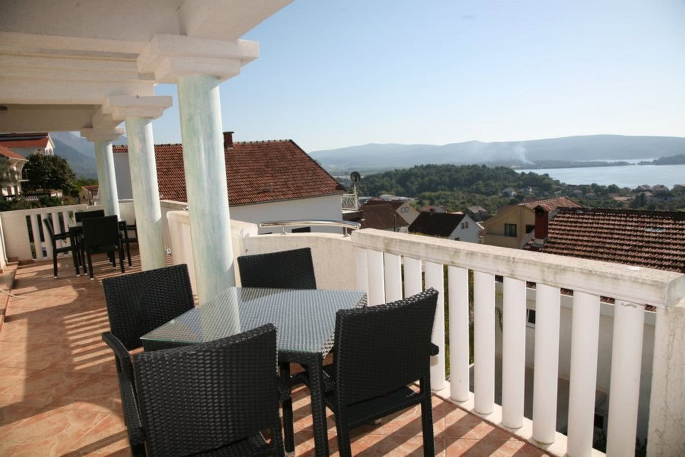 Terrasse der Villa in Tivat, Montenegro: geflochtene Stühle, Glastisch und Panoramablick auf das Meer und die Berge.