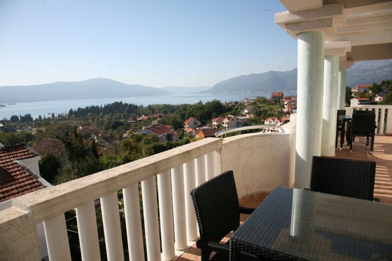 Geräumige Terrasse der Villa in Tivat, Montenegro, mit Panoramablick auf das Meer und die Berge sowie geflochtenen Möbeln zum Entspannen.