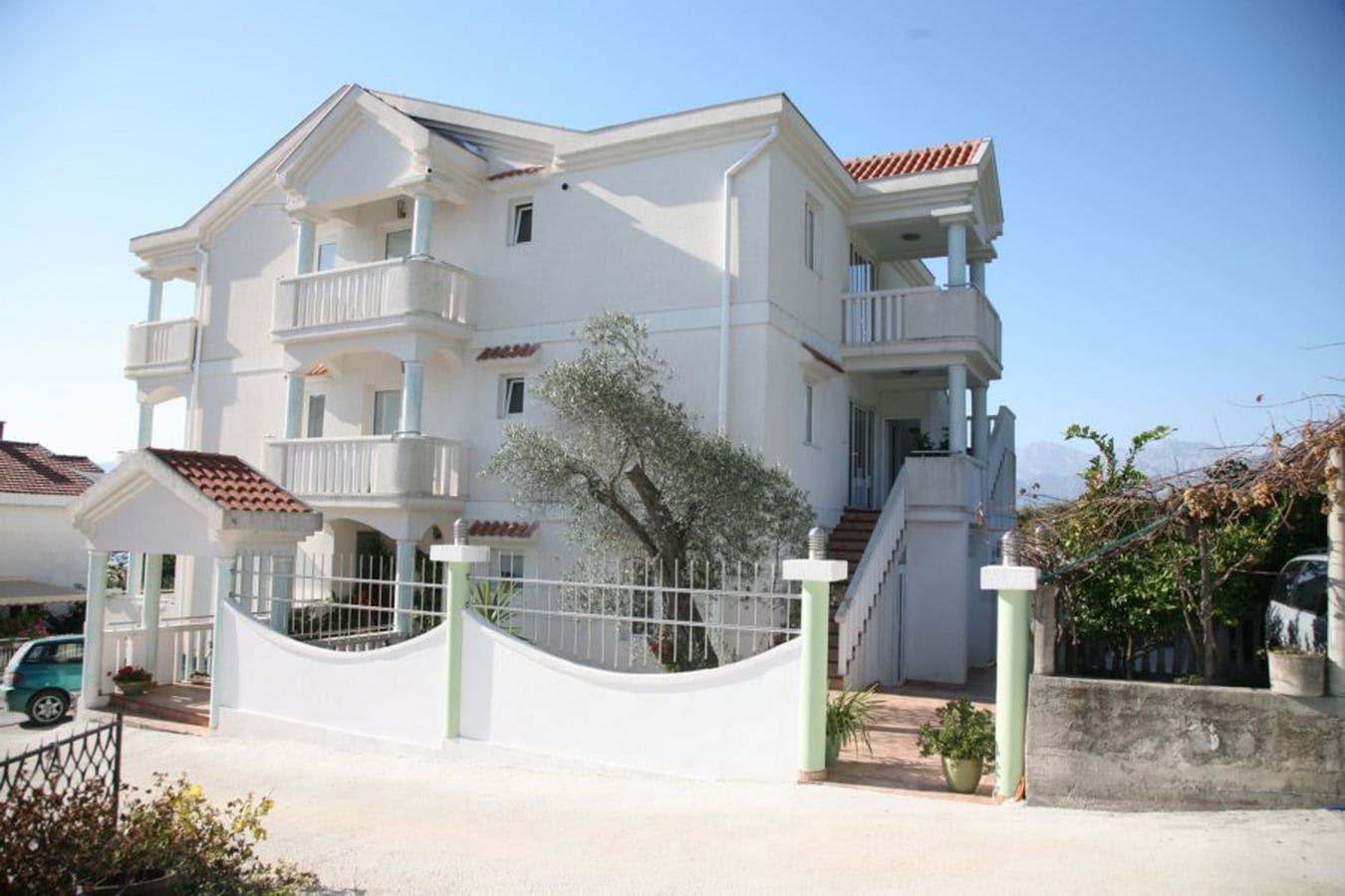 Dreistöckige weiße Villa mit Balkonen und eingezäuntem Grundstück in der Stadt Tivat, Montenegro.