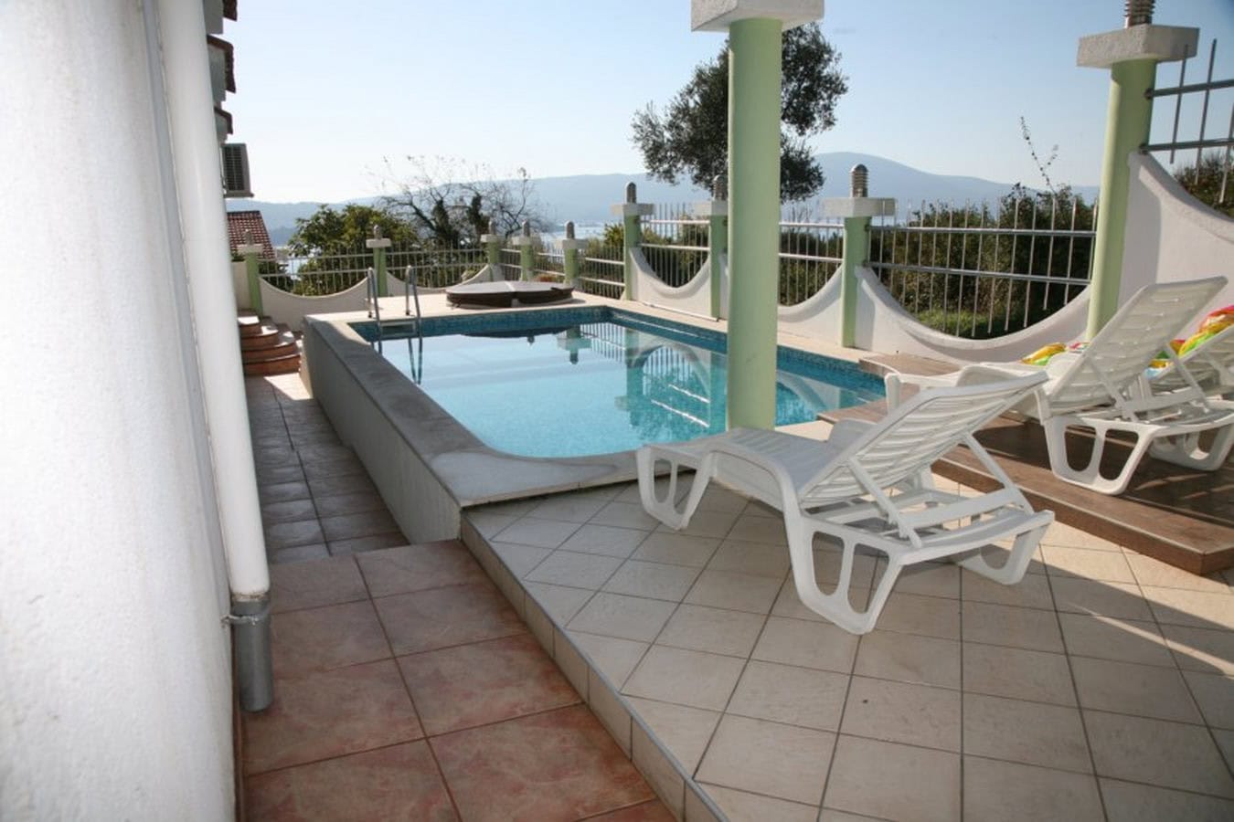 Offene Terrasse mit Pool und Liegestühlen in einer Villa in Tivat, Montenegro, mit Panoramablick auf das Meer und die Berge.